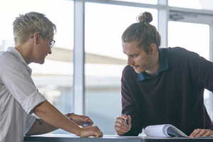 two people looking at paper on table